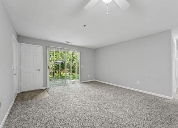 A spacious room with a carpeted floor and a ceiling fan.